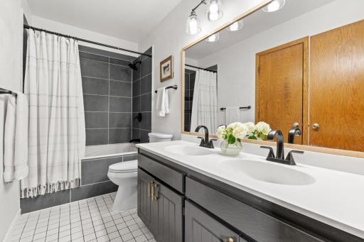 Full bath updated in 2021 with a double vanity, tiled tub and shower surround, and an oak framed mirror.