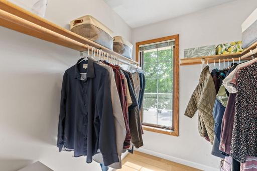 Primary bedroom closet with double hanging rods, upper shelving, and a window.