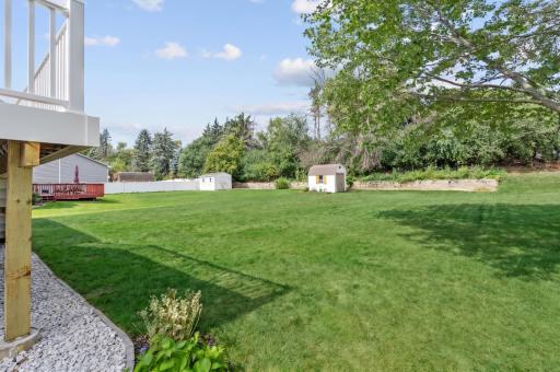 Backyard with a level lawn, storage shed, and mature trees along the rear property line.