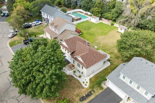 Aerial view of the home and backyard showing the deck, lawn, and mature tree canopy.