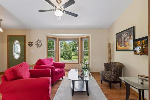 The front foyer, complete with coat closet, flows directly into the spacious living room, where hardwood flooring, a beautiful bay window and a ceiling fan with light create a comfortable gathering space.