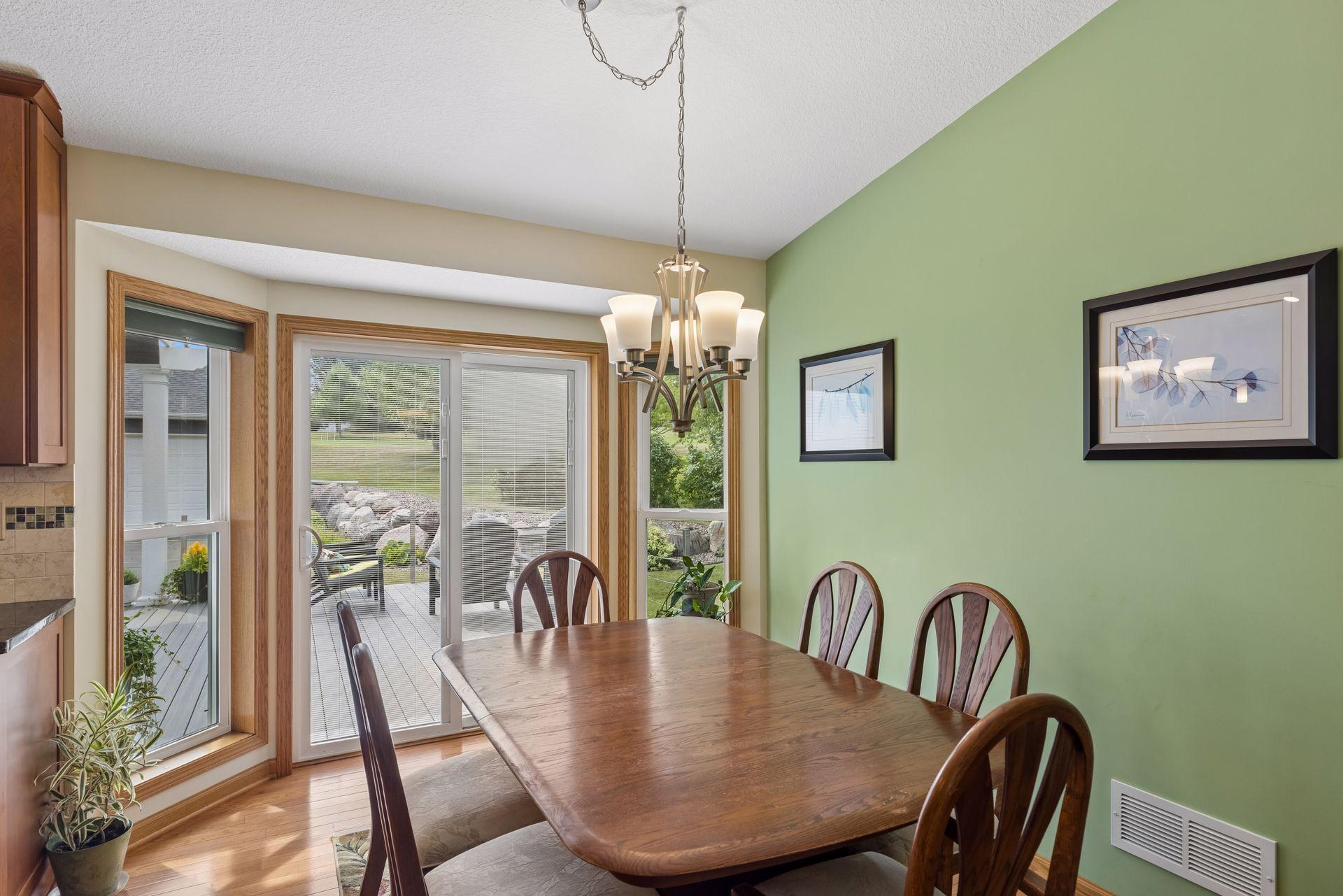 The dining area continues the hardwood flooring and offers chandelier lighting and sliding door access that opens directly to the deck.