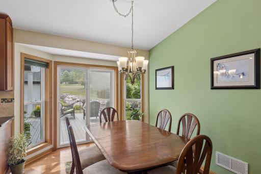 The dining area continues the hardwood flooring and offers chandelier lighting and sliding door access that opens directly to the deck.