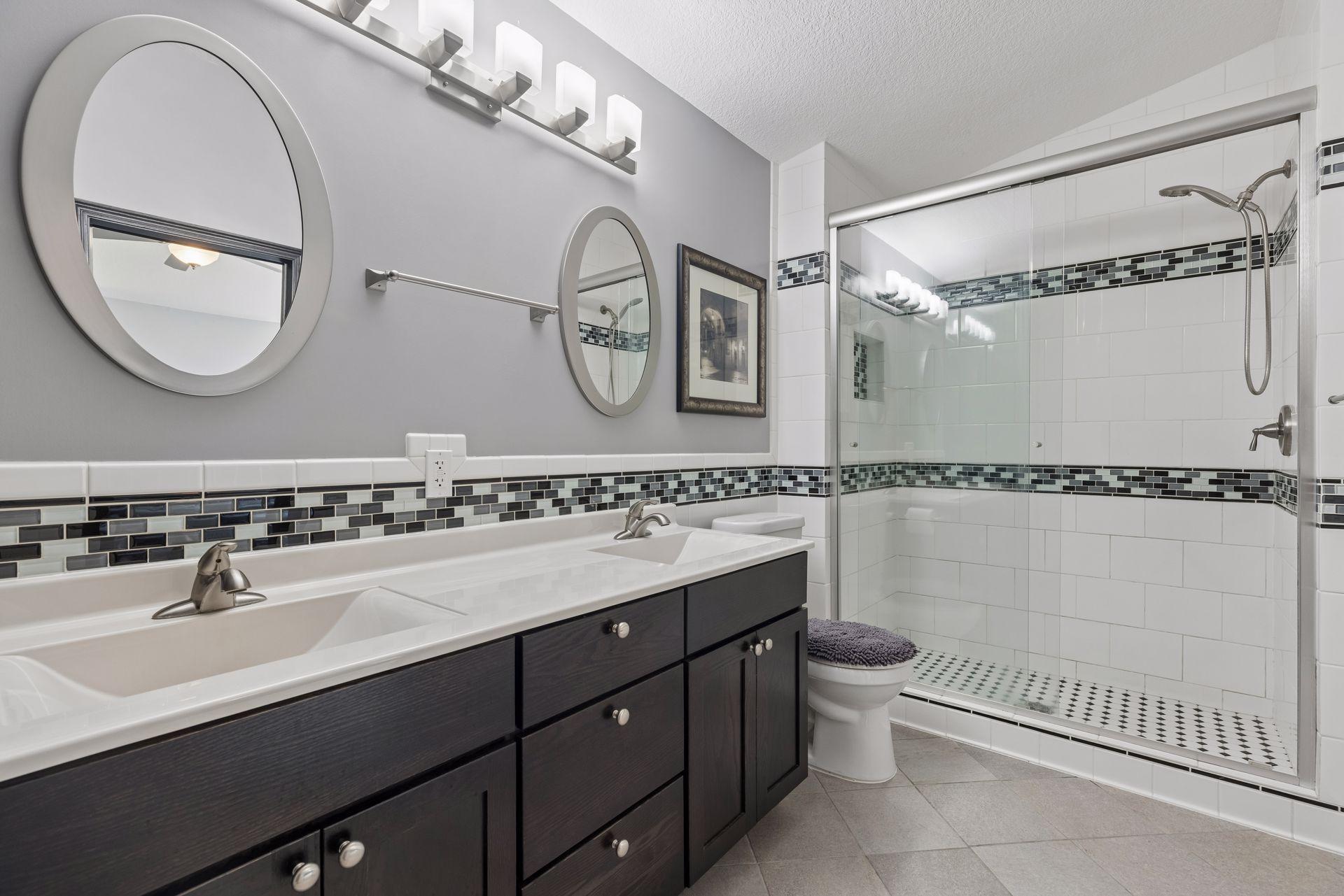 The primary 3/4 bathroom showcases thoughtful updates, including heated tile flooring, a tiled shower with glass door, linen closet. and a double vanity.