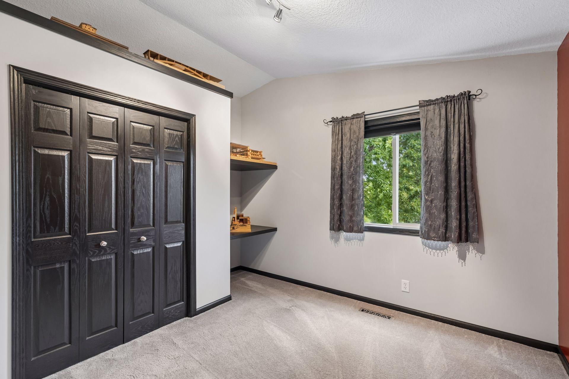 Vaulted ceilings enhance the second upper level bedroom, complemented by carpet flooring, a double window, overhead track lighting, built-in shelving and a double closet.