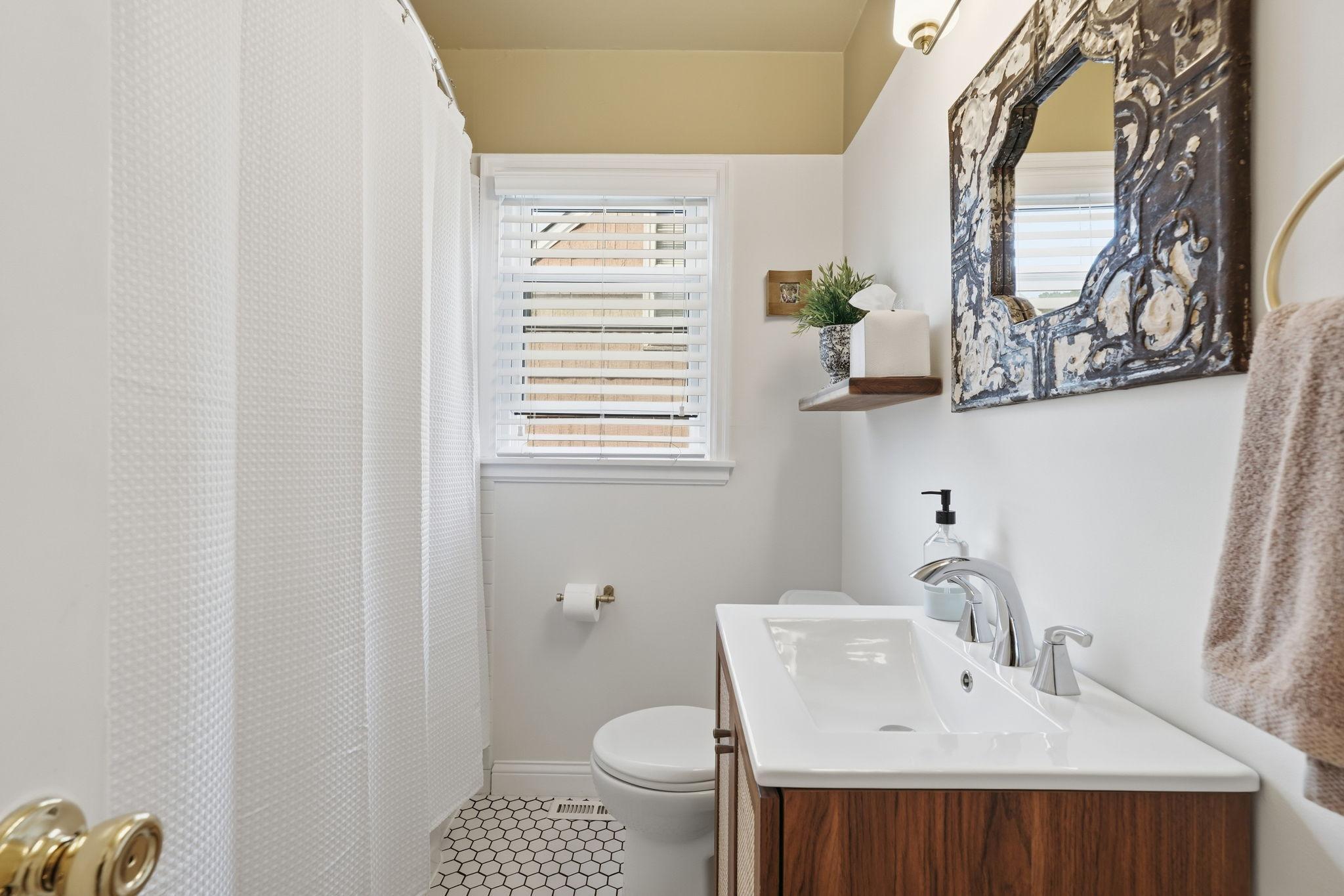 Main floor full bathroom with updated vanity and tile floor.
