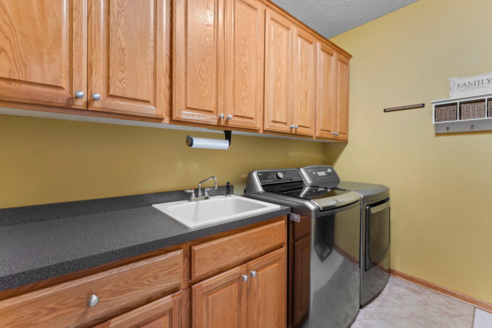 Convenient main floor laundry room with a sink and plenty of storage space