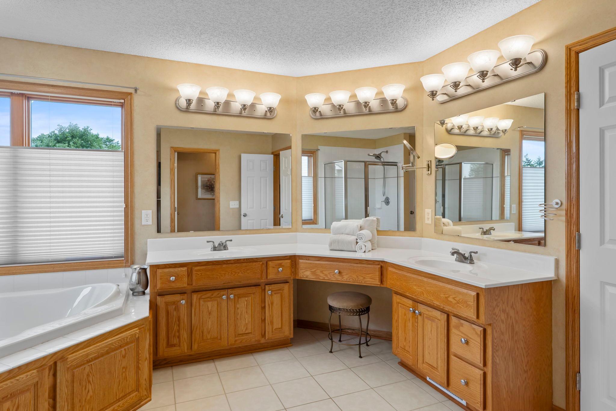 Primary bathroom includes dual sinks with a vanity, whirlpool tub and walk-shower