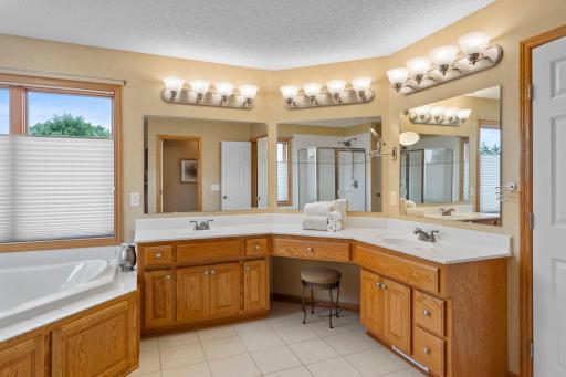 Primary bathroom includes dual sinks with a vanity, whirlpool tub and walk-shower