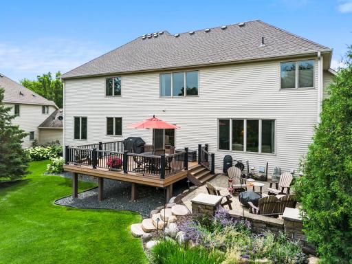 A backyard made for relaxing and entertaining with a spacious deck and patio surrounded by gorgeous landscaping