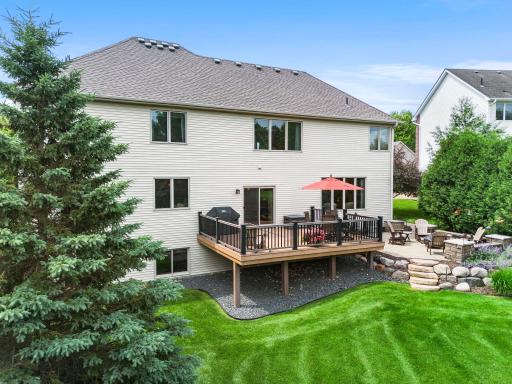 A backyard made for relaxing and entertaining with a spacious deck and patio surrounded by gorgeous landscaping