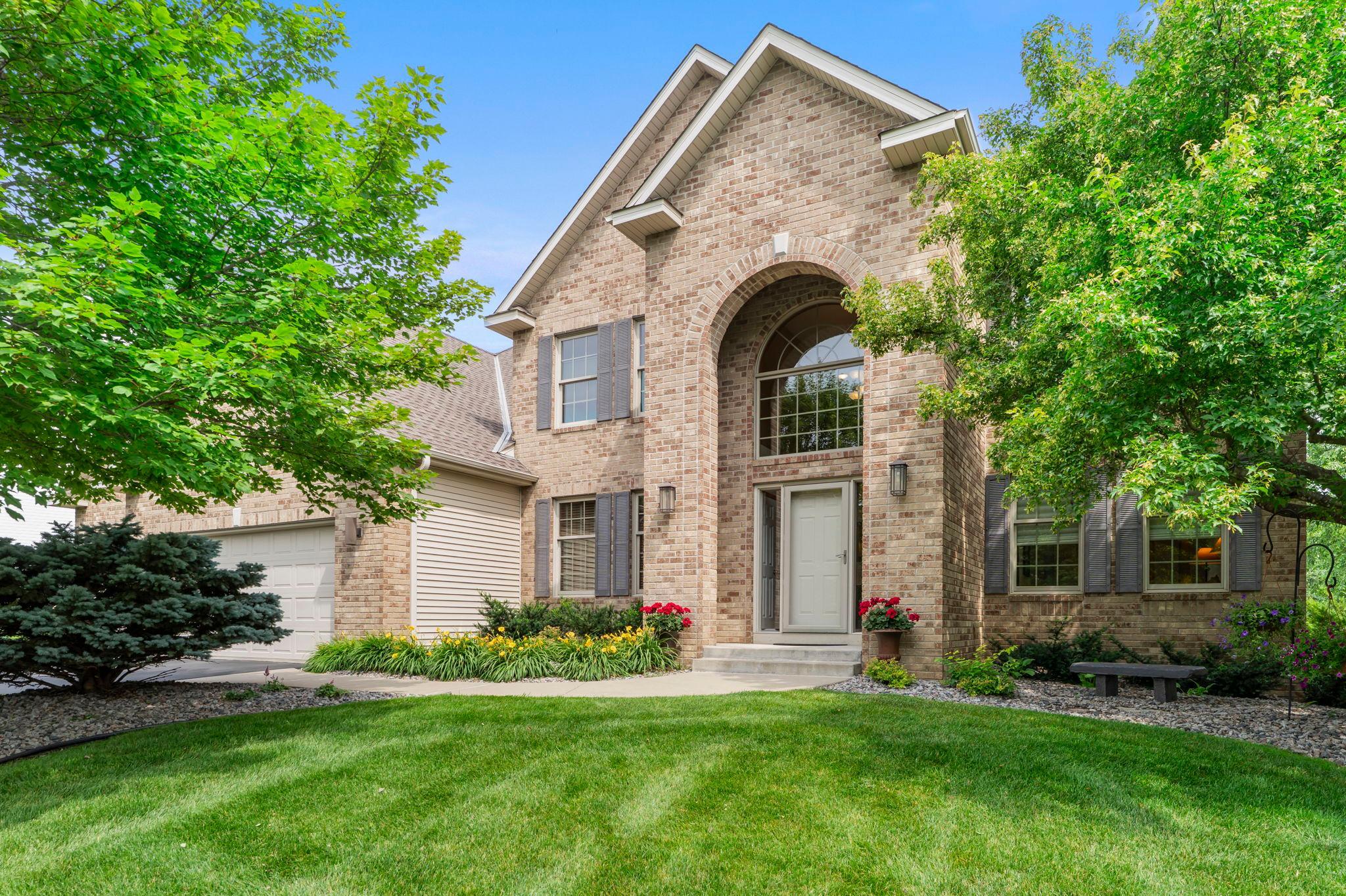 Beautiful brick exterior framed by mature landscaping and a lush front lawn