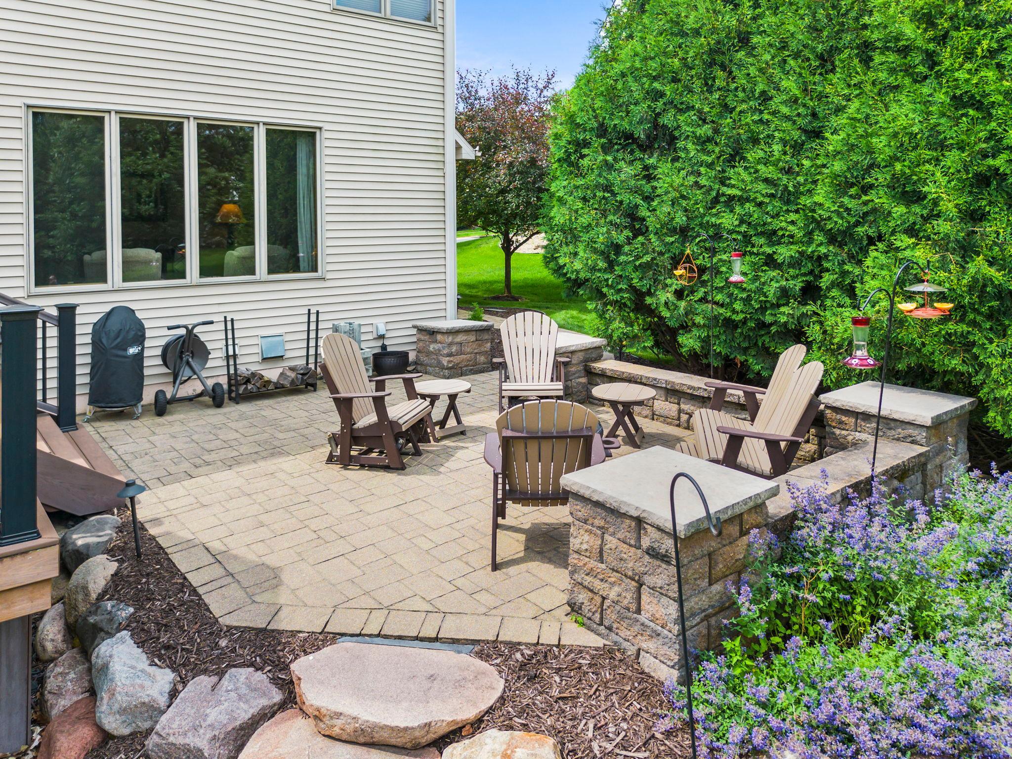 Tall, mature arborvitaes surround the patio, providing a lush backdrop and enhanced privacy