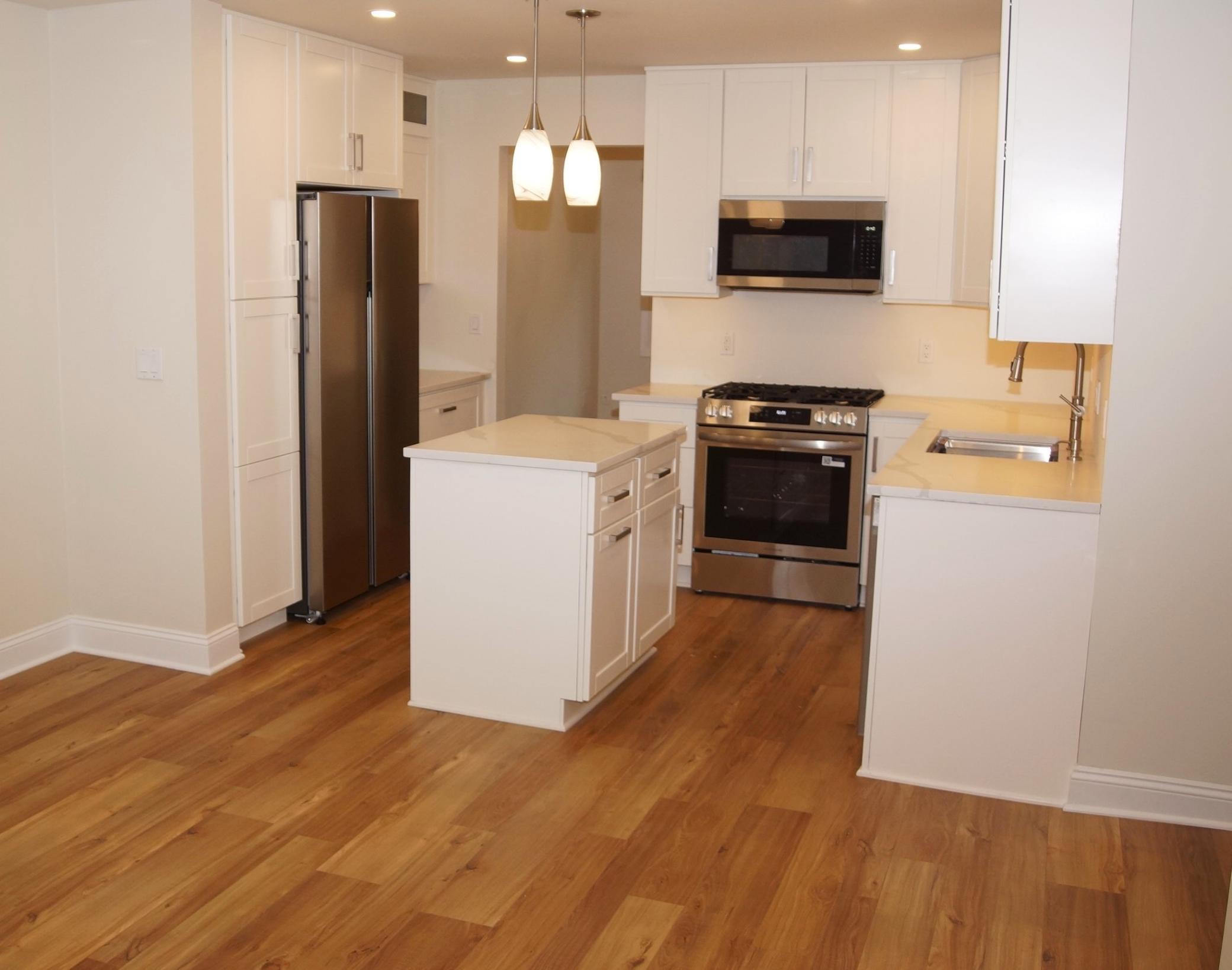 Freshly remodeled kitchen featuring new cabinetry, spacious countertops, and a functional center island. Equipped with a brand-new stainless steel appliances including a gas range, dishwasher, microwave, and side-by-side refrigerator.
