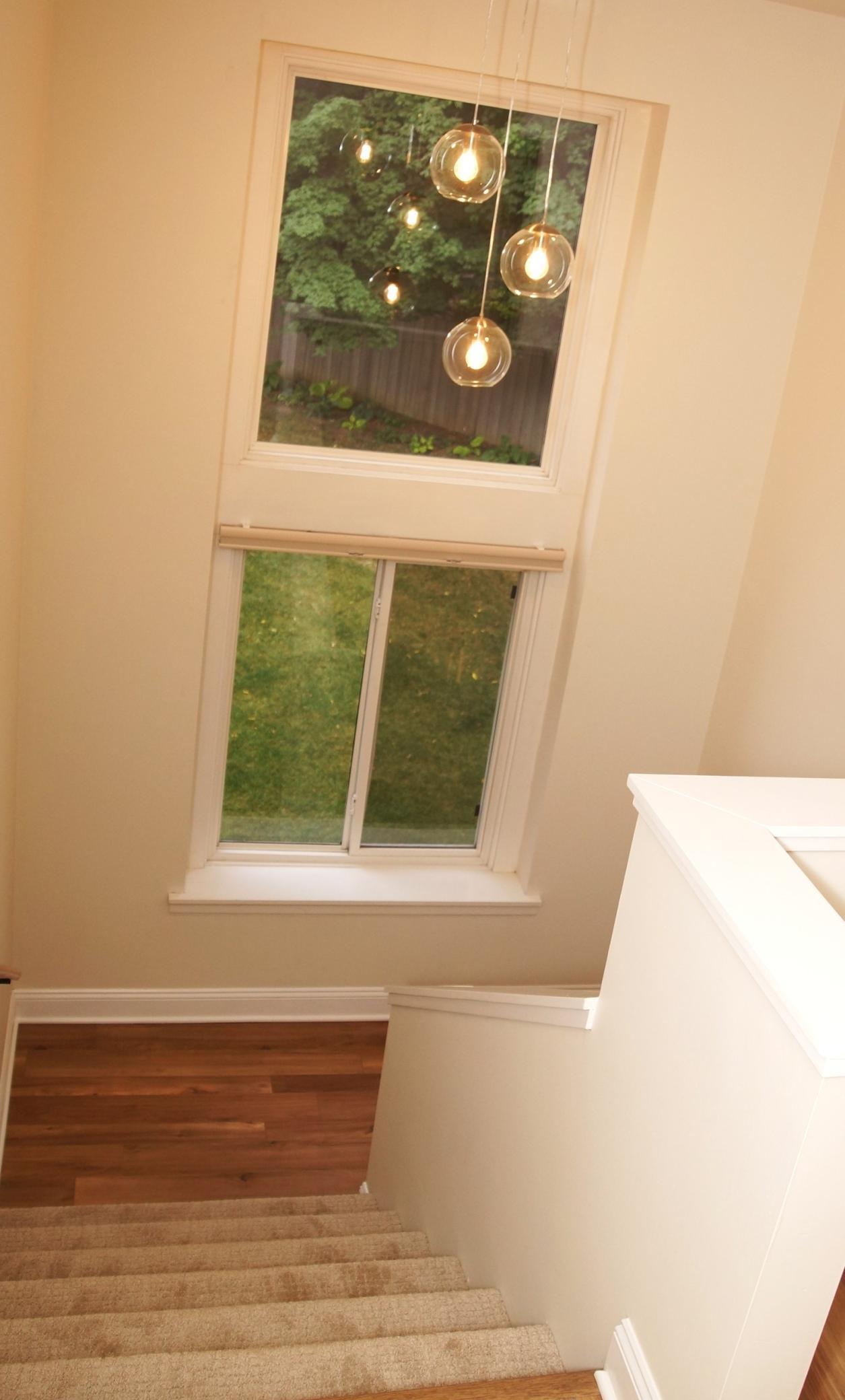 The upstairs hallway is filled with natural light streaming through the large, double-stacked windows.