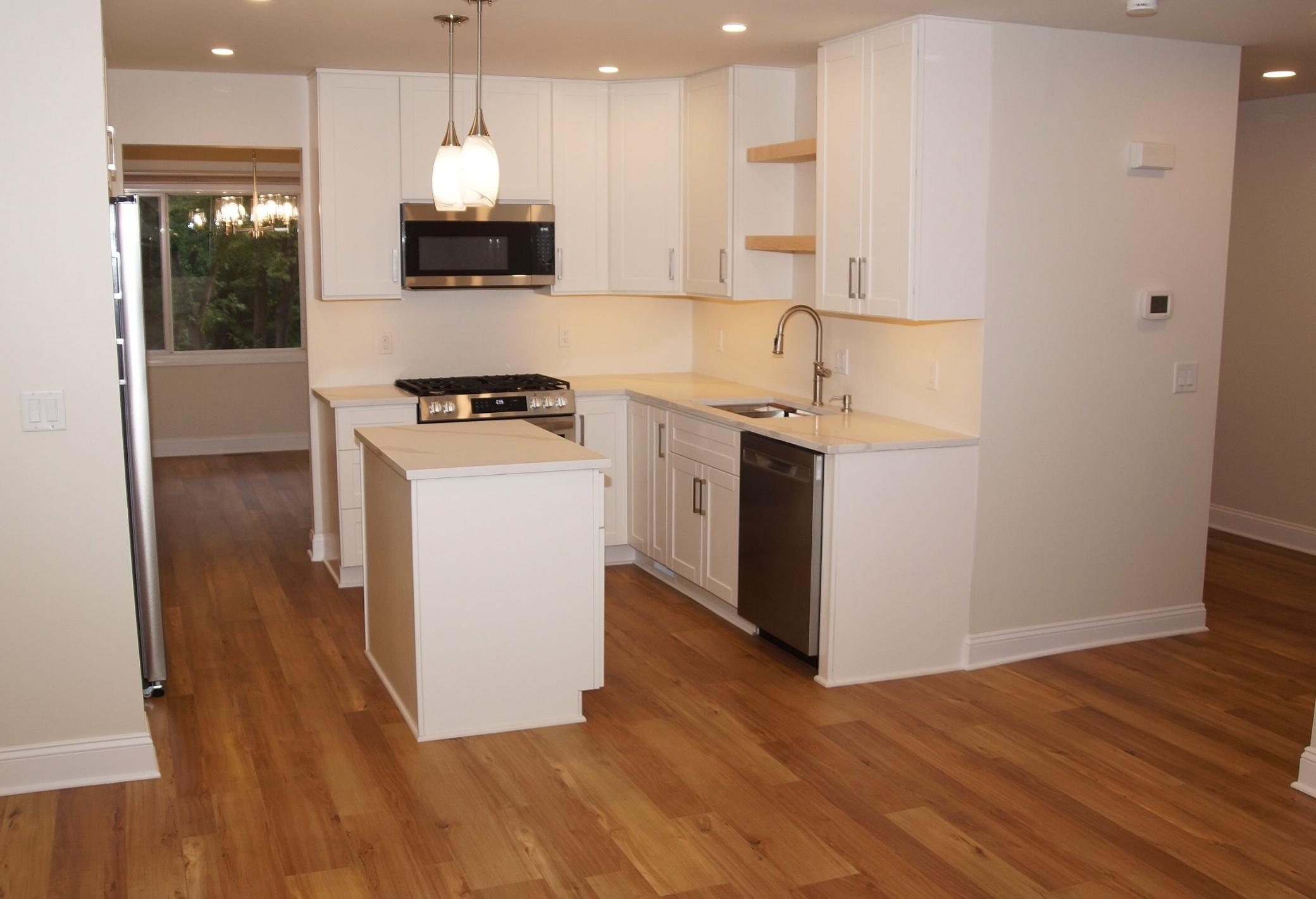 Freshly remodeled kitchen featuring new cabinetry, spacious countertops, and a functional center island. Equipped with a brand-new stainless steel appliances including a gas range, dishwasher, microwave, and side-by-side refrigerator.
