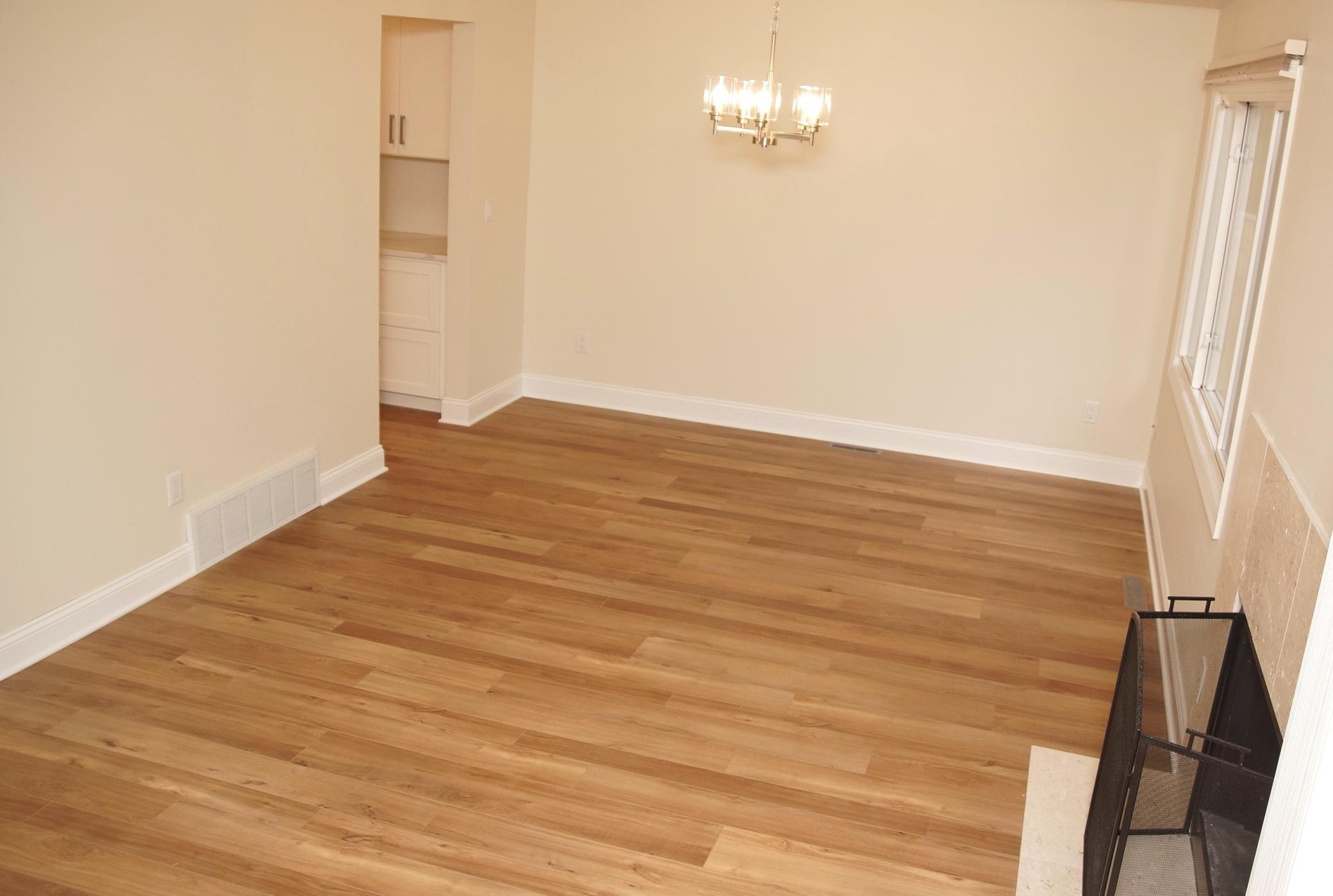 Formal Dining and Living Room area adjacent to the kitchen, featuring a wood-burning fireplace, fresh paint, brand-new flooring, and sliding glass doors that lead to a private deck.