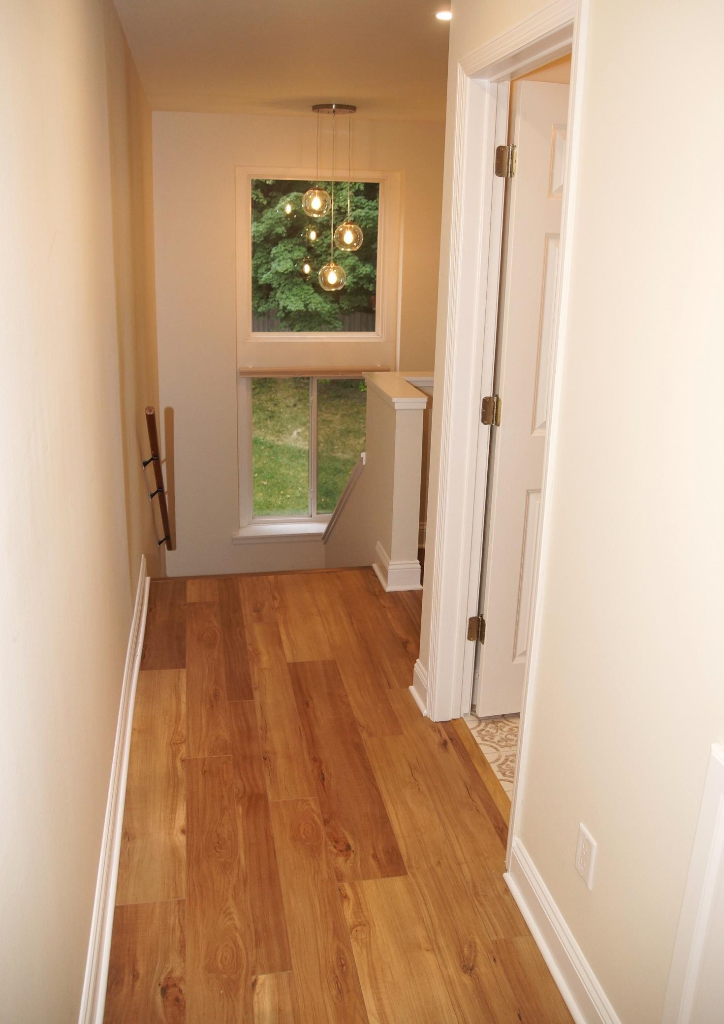 The upstairs hallway is filled with natural light streaming through the large, double-stacked windows.