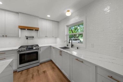 Elegant tiled backsplash adds texture and visual interest while coordinating beautifully with the quartz countertops and custom cabinetry.