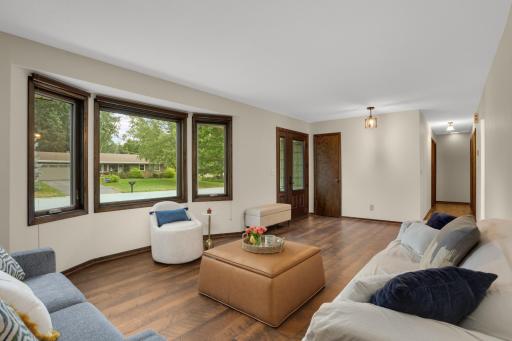 Step inside to a spacious, light-filled living room featuring beautiful flooring and a large front window overlooking the neighborhood.