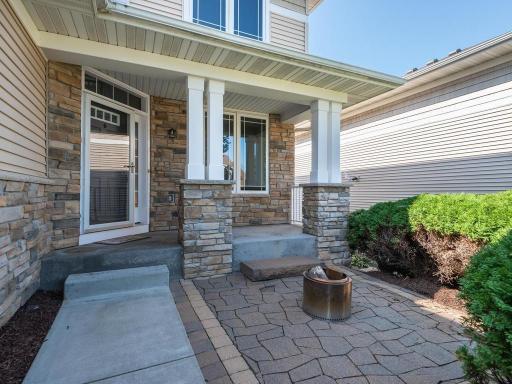Wonderful curb appeal featuring mature trees & landscaping that surrounds a charming paver patio, perfect for greeting neighbors & friends around a cozy evening fire.
