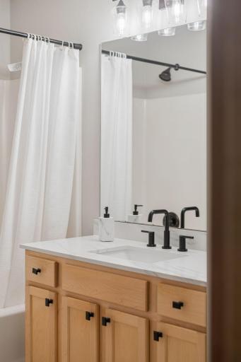 Updated bathroom vanity featuring a bright countertop, modern black fixtures, and contemporary lighting.