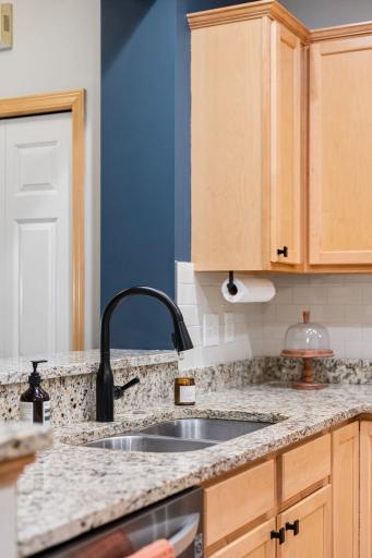 Granite countertops, double-basin sink, and modern black faucet complement the kitchen finishes.