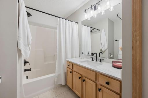 Full bathroom with updated vanity, modern fixtures, tub/shower combination, and tiled flooring.
