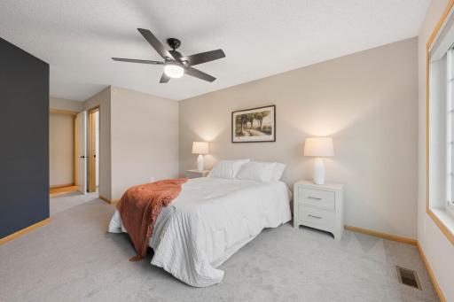 Primary bedroom offers a spacious layout, ceiling fan, and abundant natural light.