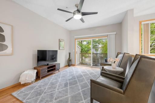 Spacious living room featuring a ceiling fan, large sliding glass door, and access to the private deck.