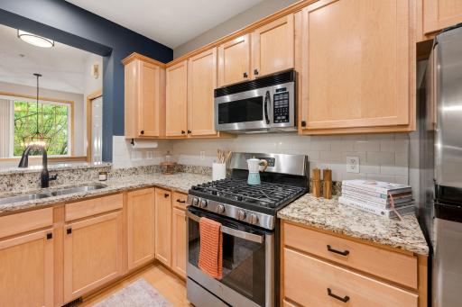 Updated kitchen with stainless steel gas range, subway tile backsplash, and abundant cabinet storage.