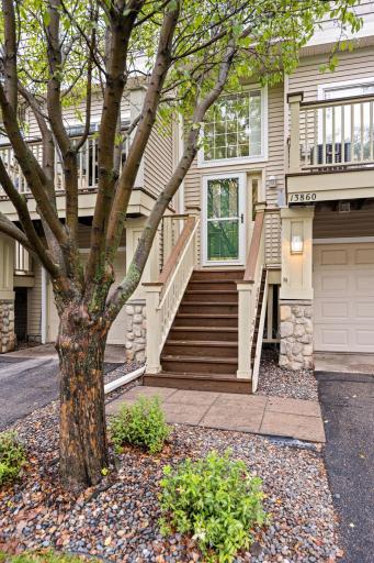 Inviting front entrance framed by mature landscaping and established trees.