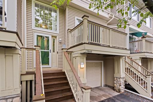 Exterior view highlighting the private deck, attached garage, and multi-level townhome design.