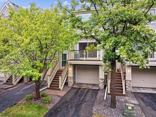 Charming townhome exterior with attached garage, private deck, and mature trees providing a welcoming setting.