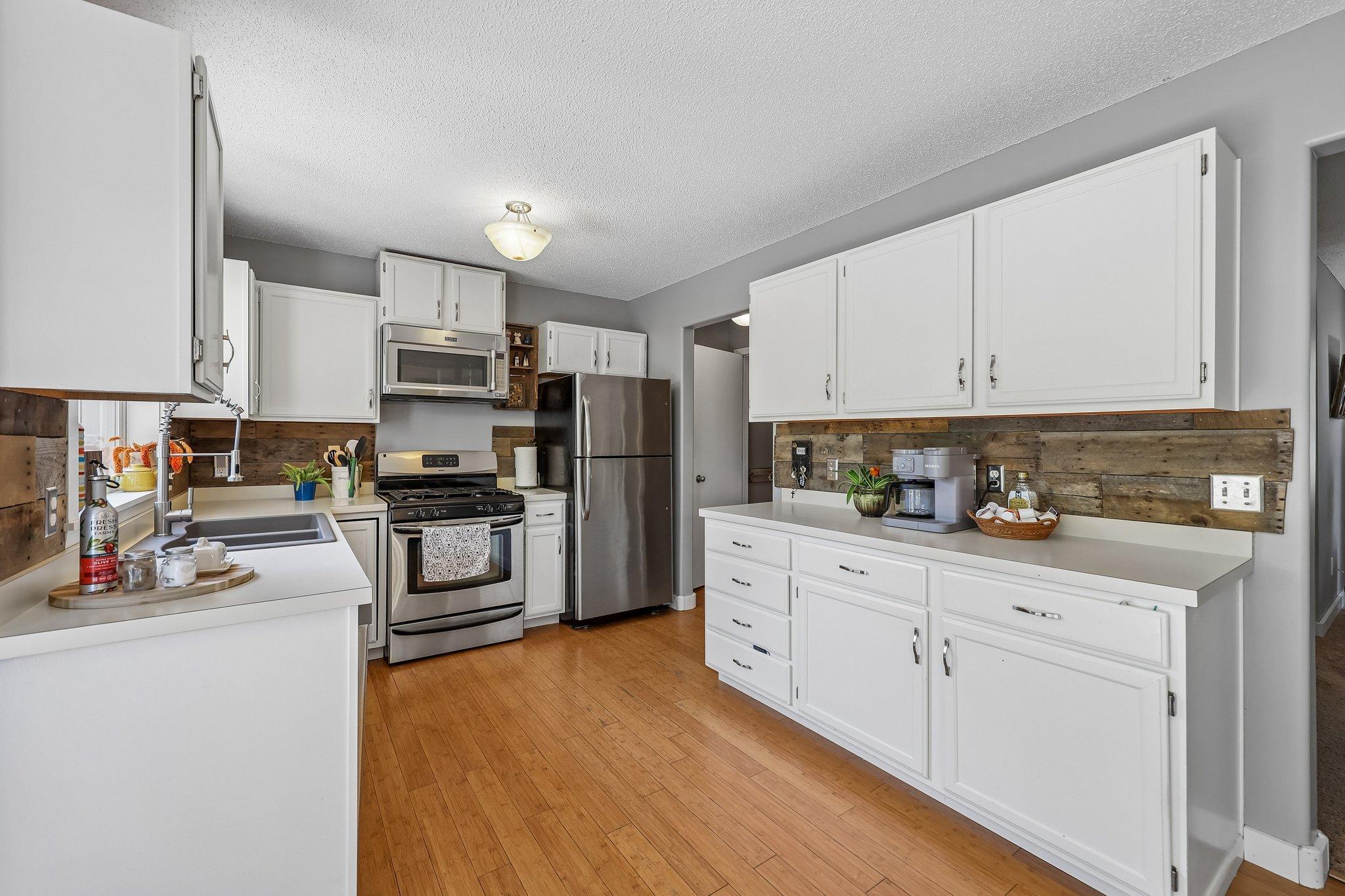 The kitchen features ample storage along with stainless steel appliances, wood floors and countertop space.
