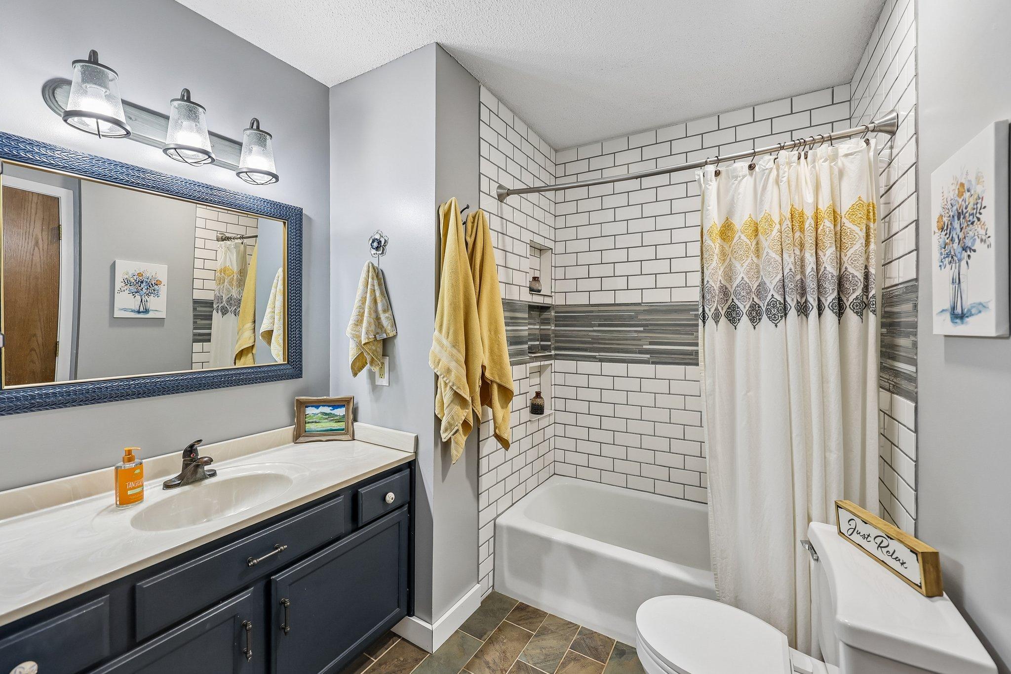 This updated walk-through bath features stylish subway tile, ample storage and tile floors.