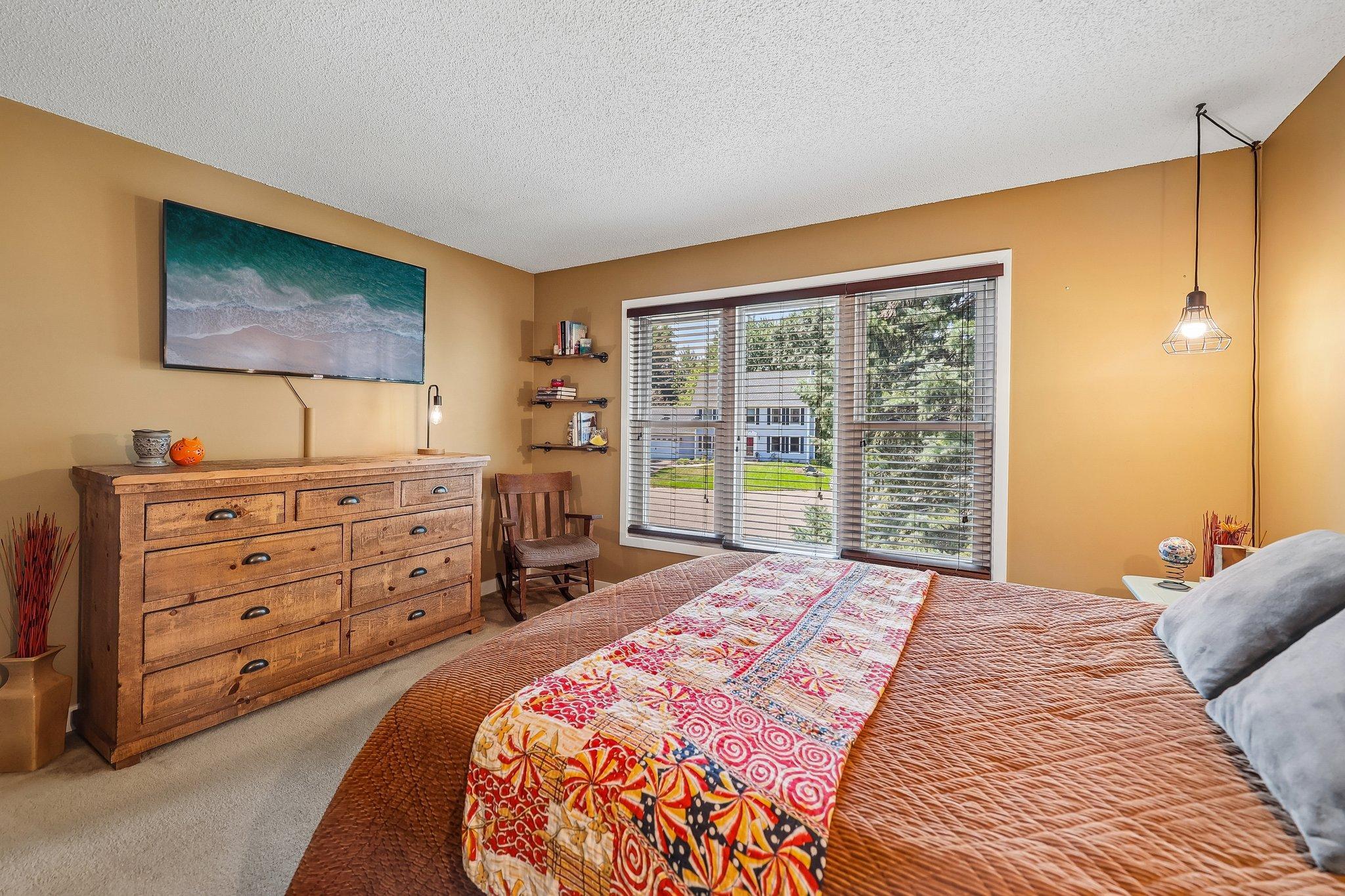 The primary bedroom features large bright windows and walk-through access to the updated bath.