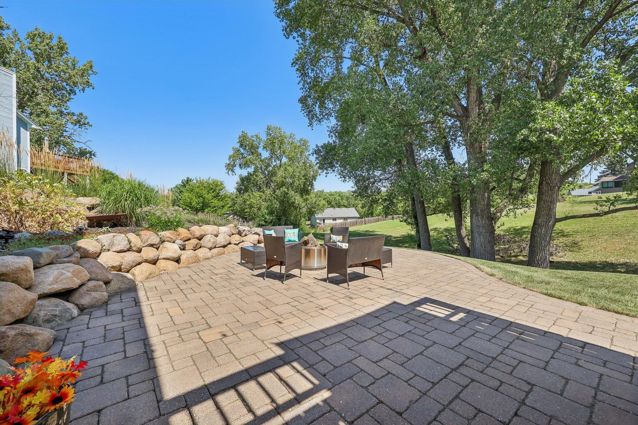 Another view of the back yard with mature trees and expansive patio.