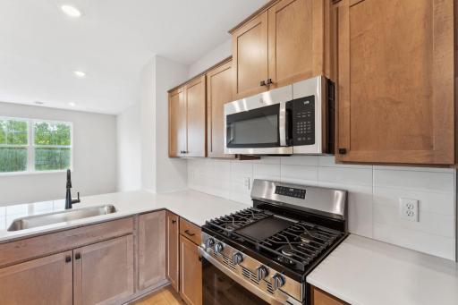 The kitchen is nicely equipped with quartz counters, stainless appliances, and tile backsplash. Similar home shown, color and options can vary.