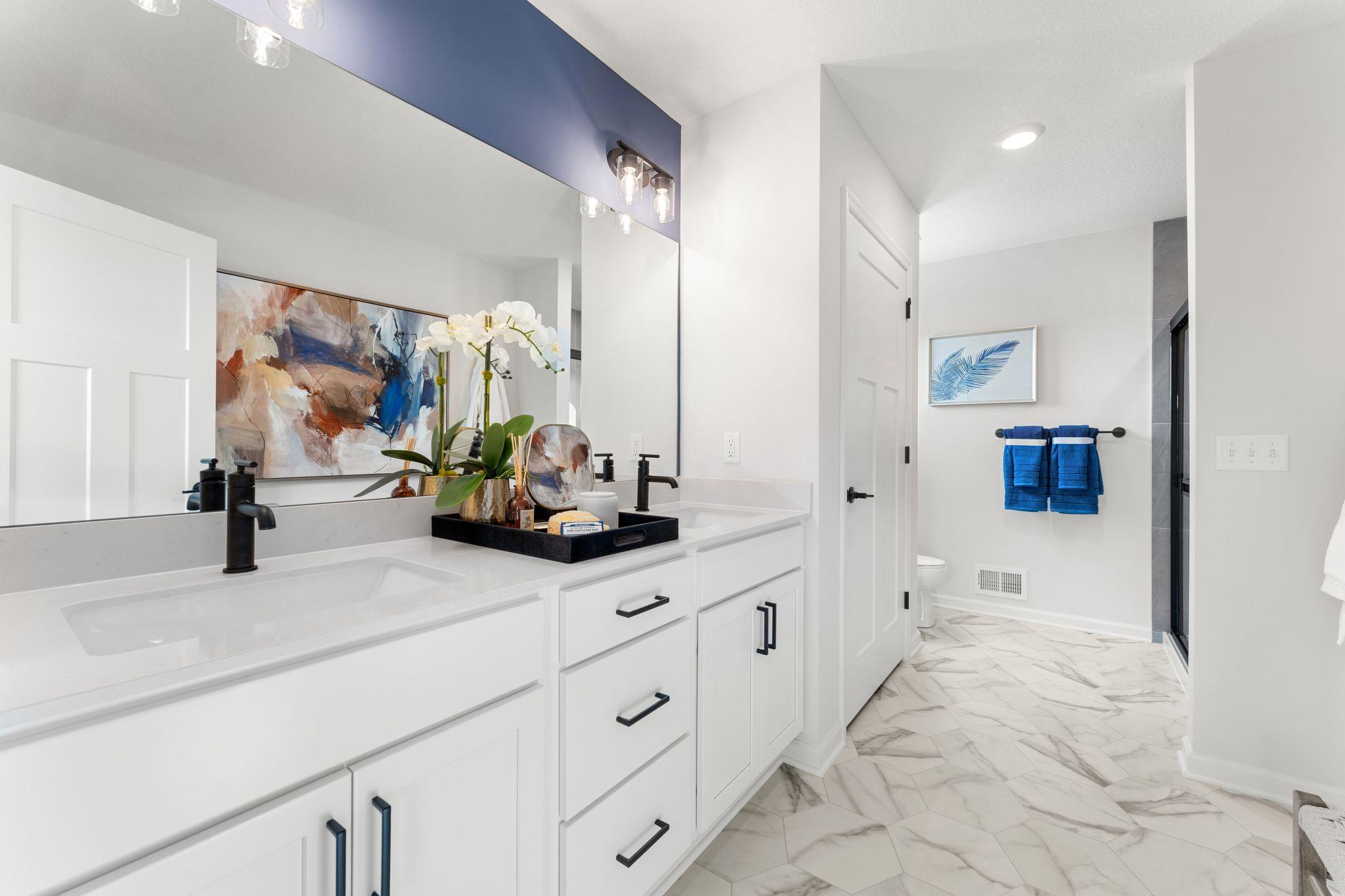 The owner's bath has everything you are looking for with a spacious closet, large two sink vanity, walk in shower and ample storage space. (Photo of model home, color and options may vary)
