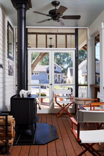 The fully screened side porch is a showstopper, featuring a wood-burning stove and swinging daybed, creating the perfect retreat in every season.