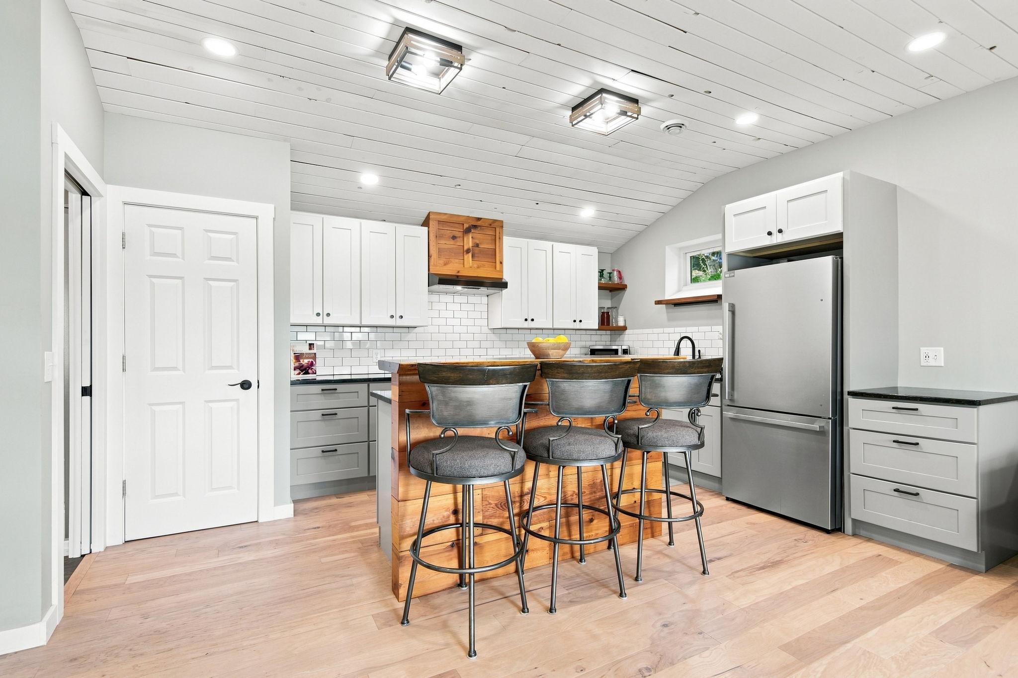 The kitchen has newer cabinetry, backsplash, appliances, granite tops, and custom wood bar top.