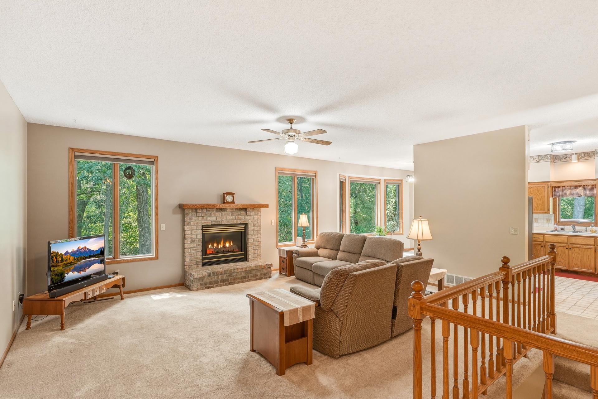 Spacious Main-Level Living Room Featuring a Cozy Gas Fireplace and Large Windows that Bring in Abundant Natural Light while Showcasing Views of the Beautiful Rear Yard Setting