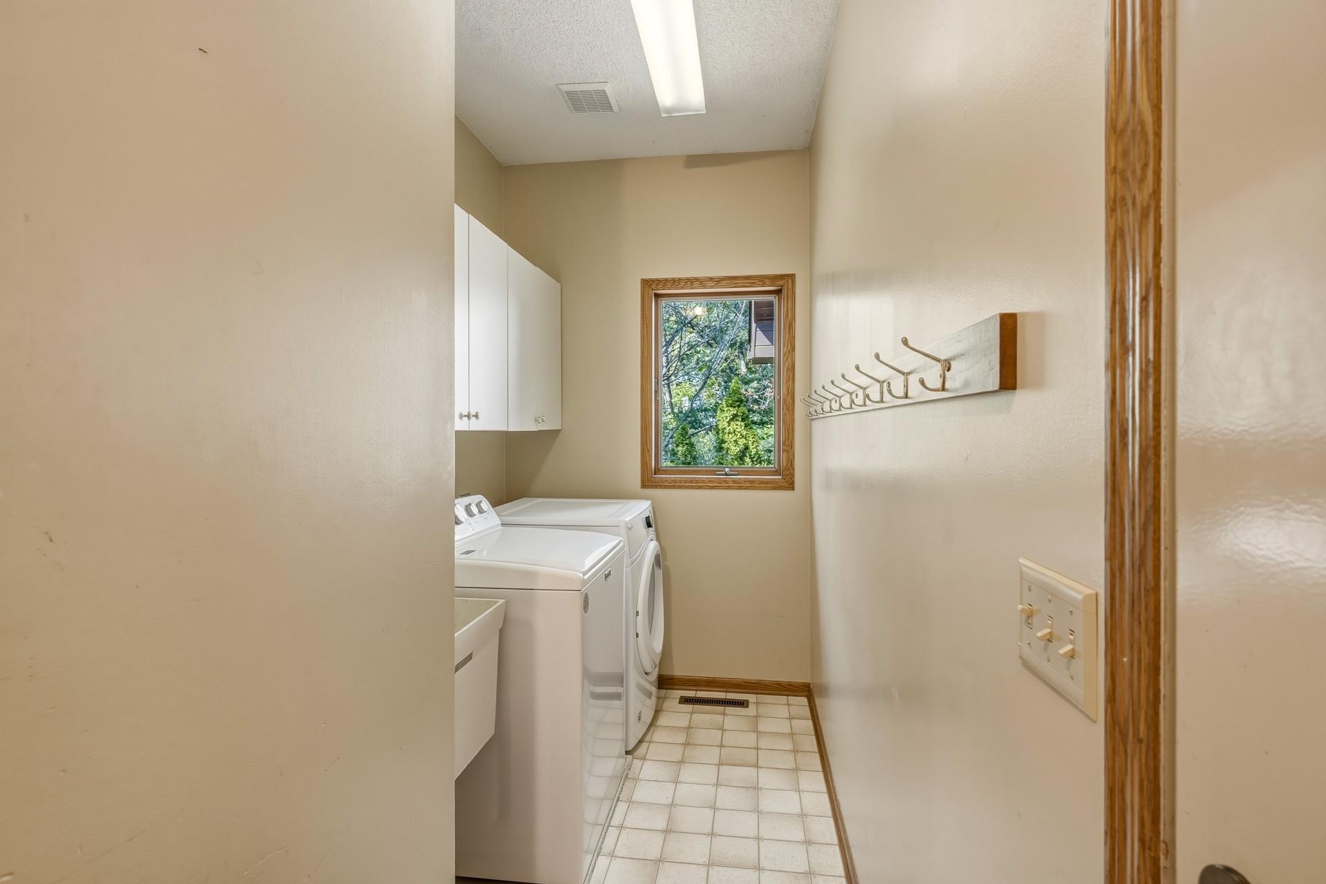 Main-Level Laundry/ Mudroom Area Features Cabinet Storage, a Utility Sink, and Washer and Dryer- All Conveniently Located Near the Garage Entrance