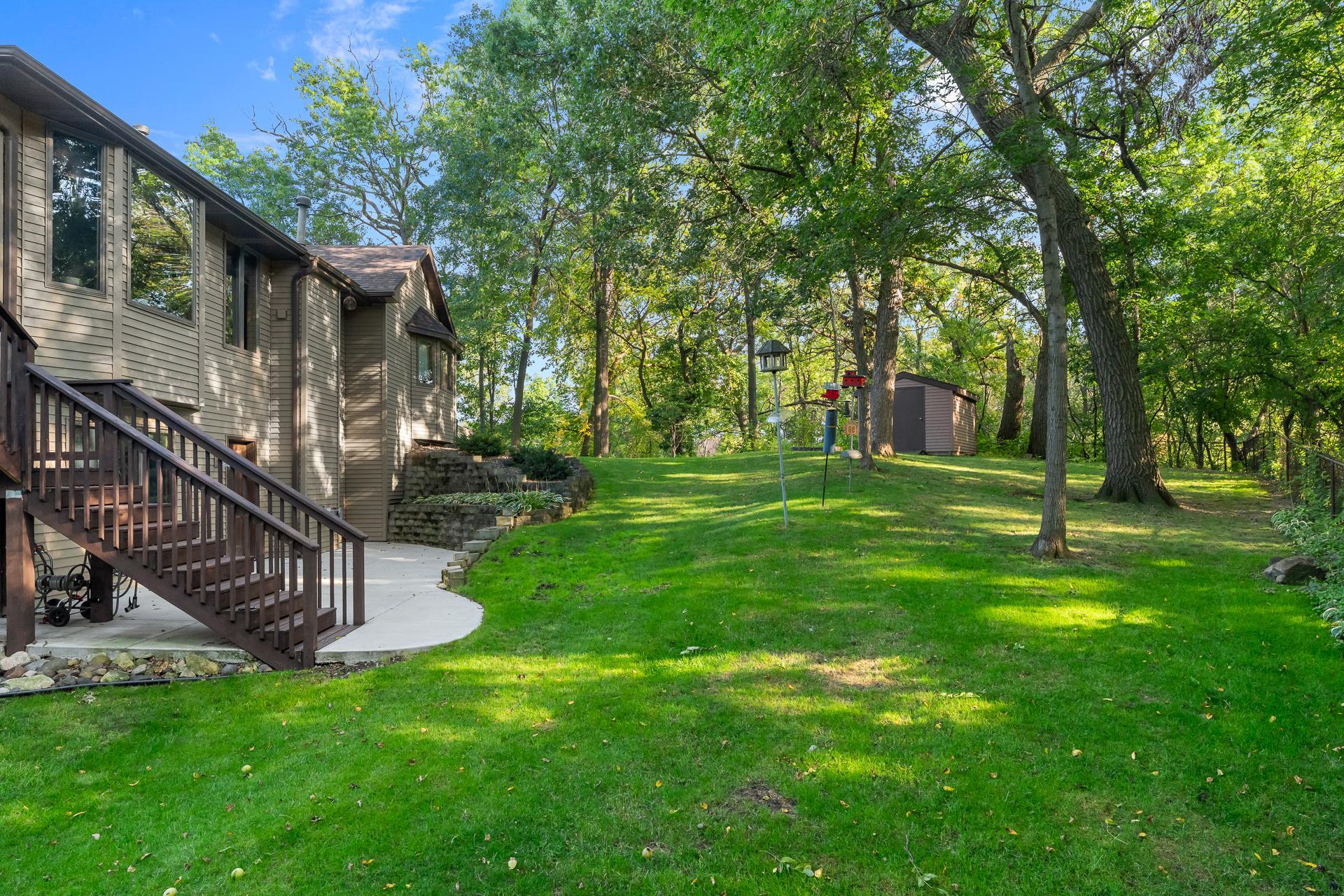 Spacious Backyard Surrounded by Mature Trees and a Wooded Backdrop, Offering Plenty of Room to Enjoy the Outdoors along with Convenient Access to the Patio and Deck