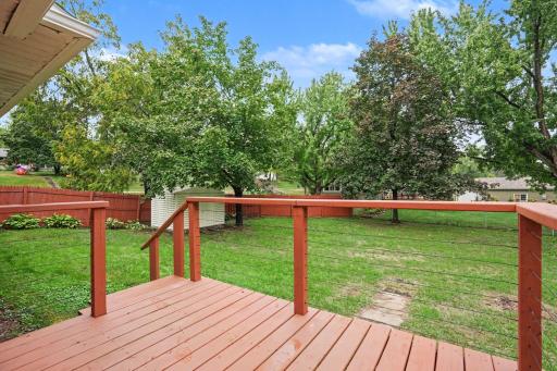 Back deck overlooking large fully fenced in back yard with storage shed and mature trees.