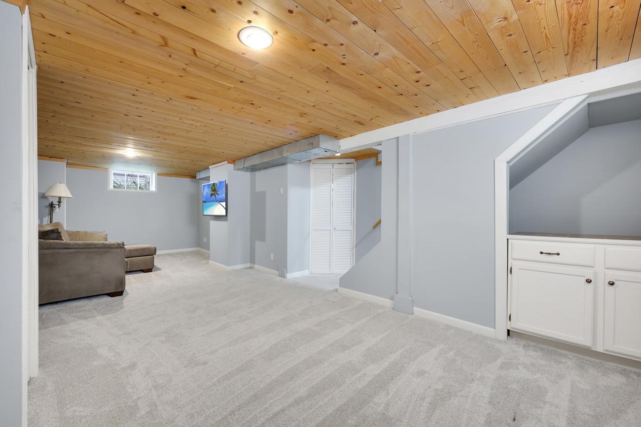 Lower-level family room with new carpeting and a warm wood-paneled ceiling.