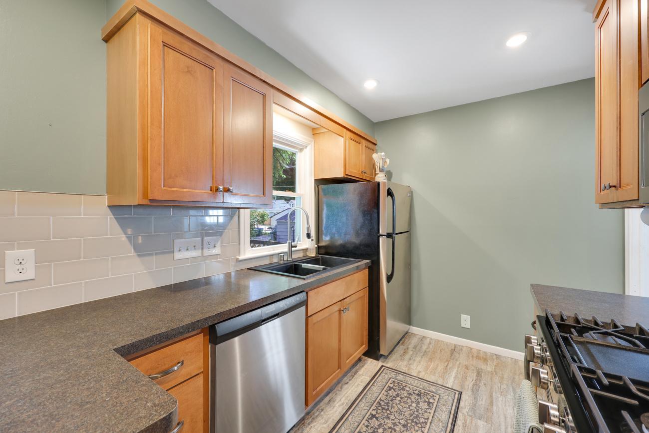 Kitchen features updated countertops, tile backsplash, and stainless steel appliances.