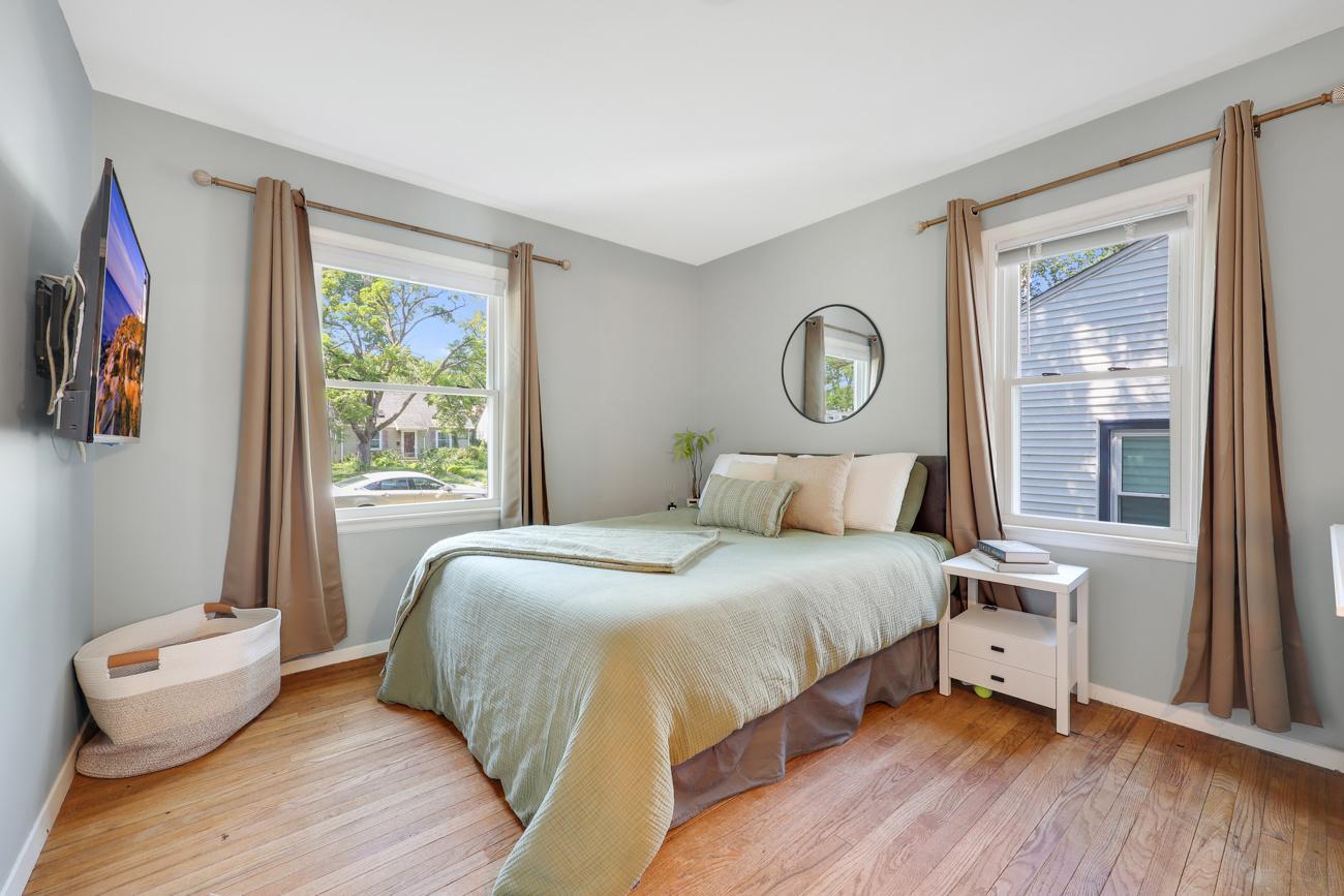 Bright main-level bedroom with hardwood floors and windows on two sides.