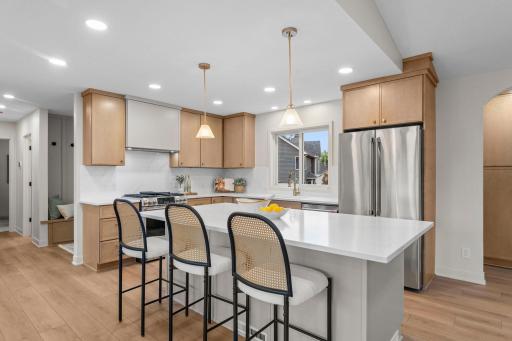 At the heart of the home, the beautifully reimagined kitchen showcases premium Café stainless steel appliances, including a gas range with sleek hood vent.